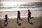 Silhouettes of family jogging along sea beach at sunrise. Outdoor workout, silhouettes of runners, sport and healthy