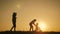 Silhouettes family is together at sunset. Young boy learning to ride bicycle, father teach his son to ride a bike in the