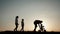 Silhouettes family is together at sunset. Young boy learning to ride bicycle, father teach his son to ride a bike in the