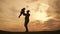 Silhouettes father and little son playing on the meadow at the sunset time. Concept of friendly family.