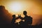 Silhouettes of father and son hiking in sunset mountains at sea