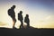 Silhouettes of father and two kids hiking at sunset