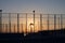 Silhouettes of a fenced public playground with sunset sky background