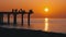 Silhouettes of Fishermen with Fishing Rods at Sea Sunset Sitting on the Pier. Slow Motion.