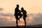 Silhouettes of fit mixed race couple stretching and training together on the rocky mountains background. Sport fitness