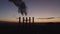 Silhouettes of five cooling towers against the backdrop of a big city and sunset. Beautiful sunset over a smoking