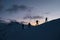 Silhouettes of four skiers on the highest point of the mountain against the background of the mountain peaks in the fog