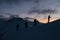 Silhouettes of four skiers on the highest point of the mountain massif after sunset