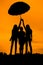 silhouettes of girls against the sky at sunset, under one umbrella