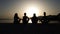 Silhouettes of girls sitting in yoga lotus pose at sunset on sea pier