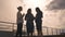 Silhouettes of a group of businessmen women against the sky and clouds. Girls in business clothes at a meeting.