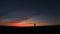 Silhouettes of the happy couple holding hands and jumping at the background of the colourful sunset.