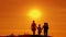 Silhouettes of happy family of four going at sunset