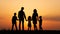 Silhouettes of happy family holding the hands in the meadow during sunset.