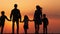 Silhouettes of happy family walking together in the meadow during sunset