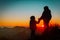 Silhouettes of happy kids hiking at sunset mountains