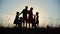 Silhouettes of happy large family dancing and embracing against the sunset background.
