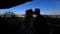 Silhouettes of happy newlywed couple tenderly kissing on the balcony at the background of the city panorama. Moving