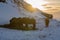 Silhouettes of a herd of Icelandic horses eating grass with the snowy ground at sunset, under a cloudy sky and orange by the first