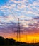 Silhouettes high voltage electric pylon in sunset background