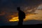 Silhouettes of hiker with backpack enjoying sunset view from top of a mountain