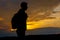 Silhouettes of hiker with backpack enjoying sunset view from top of a mountain