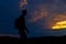 Silhouettes of hiker with backpack enjoying sunset view from top of a mountain