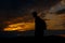 Silhouettes of hiker with backpack enjoying sunset view from top of a mountain