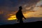 Silhouettes of hiker with backpack enjoying sunset view from top of a mountain