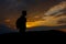Silhouettes of hiker with backpack enjoying sunset view from top of a mountain