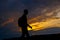 Silhouettes of hiker with backpack enjoying sunset view from top of a mountain