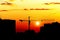 Silhouettes of houses and construction crane against setting sun, city skyline at sunset