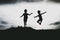 Silhouettes of kids jumping from a sand cliff at the beach