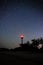 Silhouettes of the Lighthouse sandy beach and ocean against the background of the starry sky