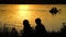 Silhouettes of little girls with fishing rods on river bank at sunset