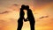 Silhouettes of loving man and woman kissing tenderly at sunset, romantic date