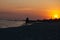 Silhouettes of a loving young couple on the ocean, against the background of the orange decline of a summer