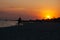 Silhouettes of a loving young couple on the ocean, against the background of the orange decline of a summer