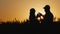 Silhouettes of male and female farmers work in a wheat field at sunset