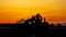 Silhouettes of a man taking a photo of a sunrise and his dog on a farm tractor