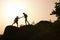 Silhouettes of man and woman helping each other to climb on hill