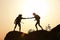 Silhouettes of man and woman helping each other to climb on hill