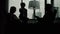 Silhouettes of man and women working in dark office using devices talking and making phone calls