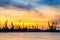 Silhouettes of mechanical cranes and industrial cargo ships in sea port on the background of sunset