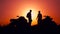 Silhouettes of men and ATVs at sunset. Men shake hands.