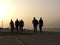Silhouettes of men walking together on the corniche of Byblos/Jbeil  in a yellow mist of sunset, Byblos, Lebanon