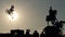 Silhouettes of monument, group of people standing underneath and jumping bikers.