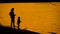 Silhouettes mother and daughter feeding seagulls at the beach at sunset.