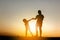 Silhouettes of mother and daughter playing at sunset evening sky background