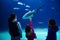Silhouettes of mother with kids in oceanarium, family with children looking at shark and fishes in aquarium